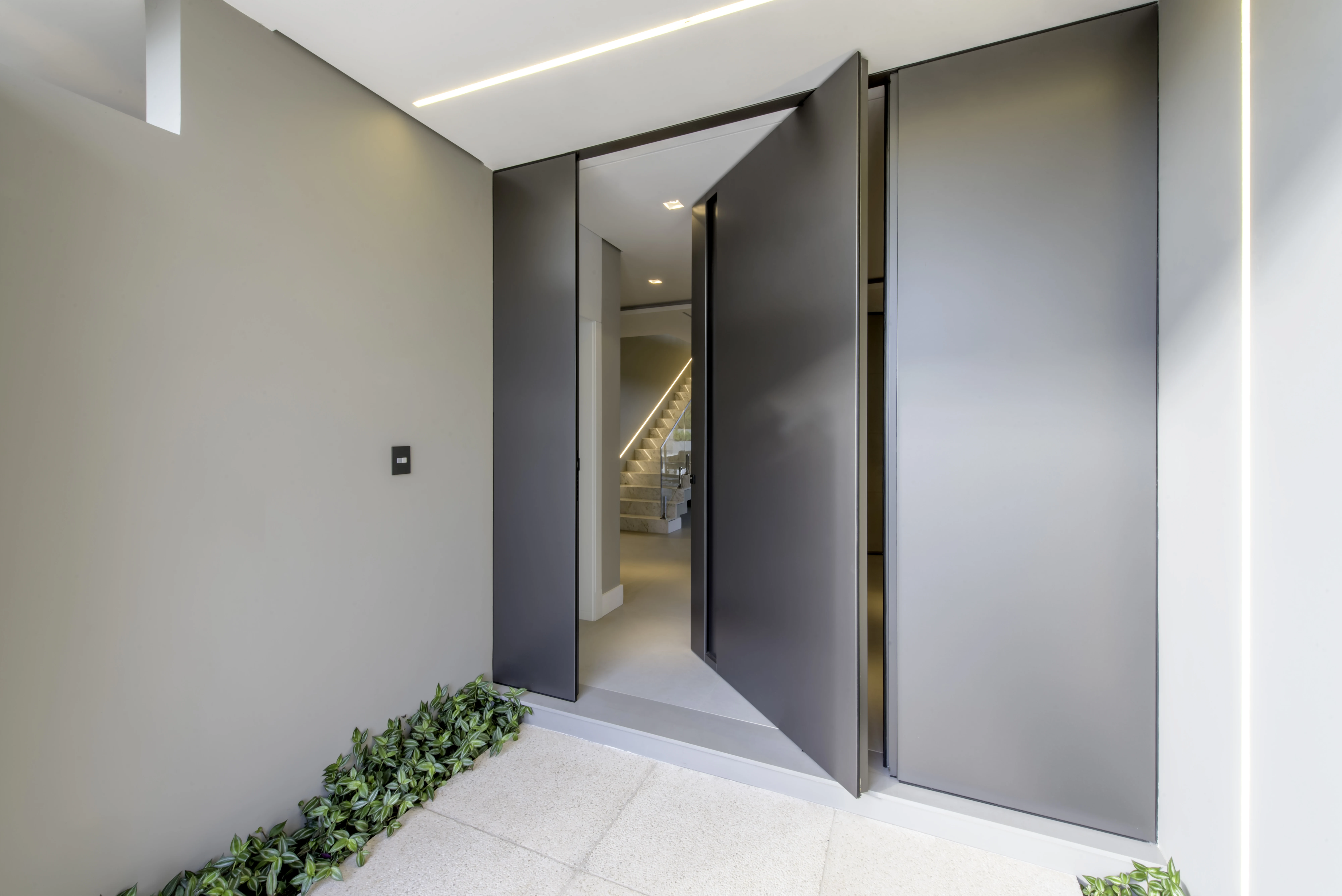 Porta de entrada contemporânea com acabamento cinza e painéis laterais