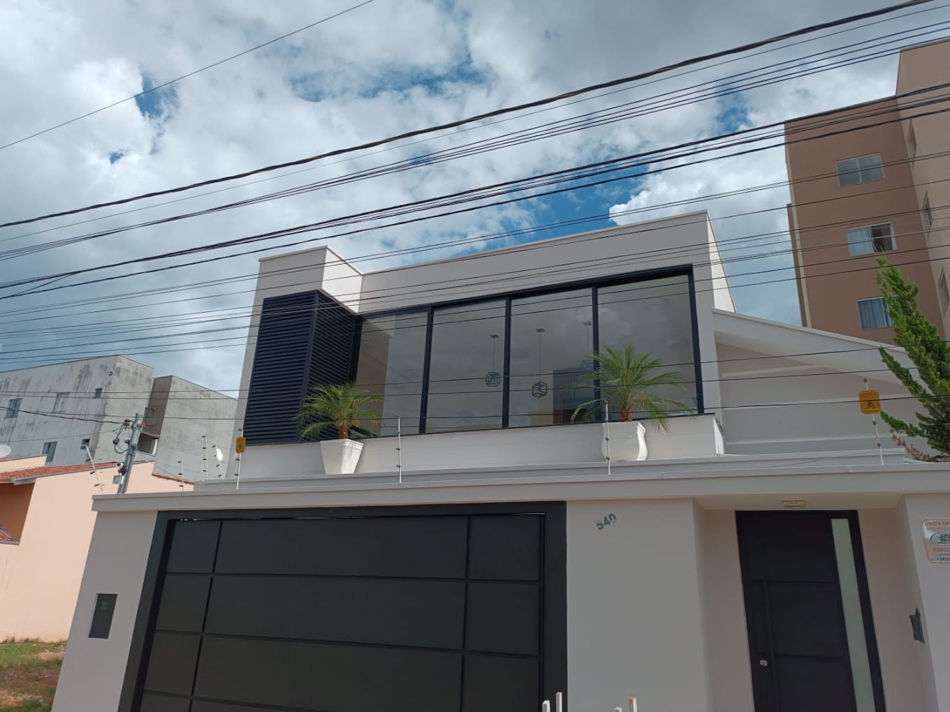 Fachada residencial com grandes áreas envidraçadas e caixilhos escuros